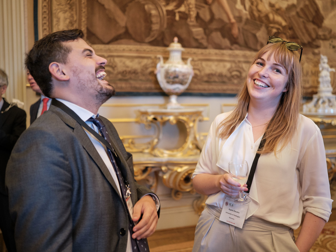 Young man and young lady laughing at evening reception in palace 