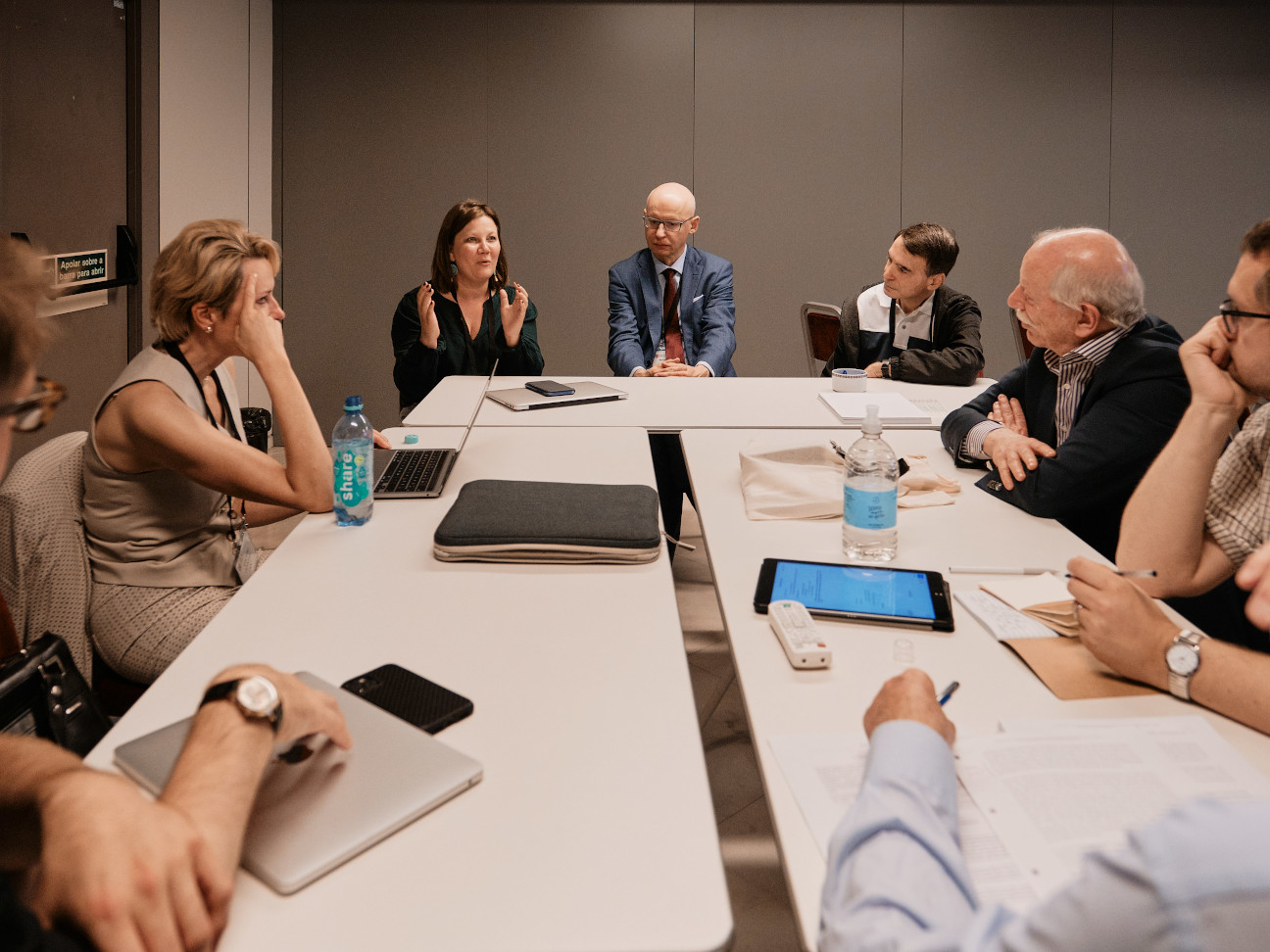 group of people meeting and sitting around a table discussing 